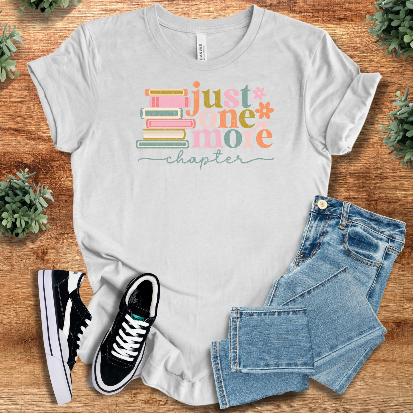 White t-shirt with '' text, flat lay styled on a wooden surface.