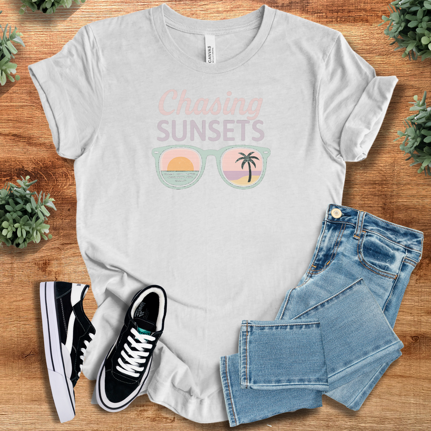 Light grey Chasing Sunsets T-Shirt with pastel sunset and palm tree design. Breathable summer tee perfect for outdoor adventures and vacation outfits.