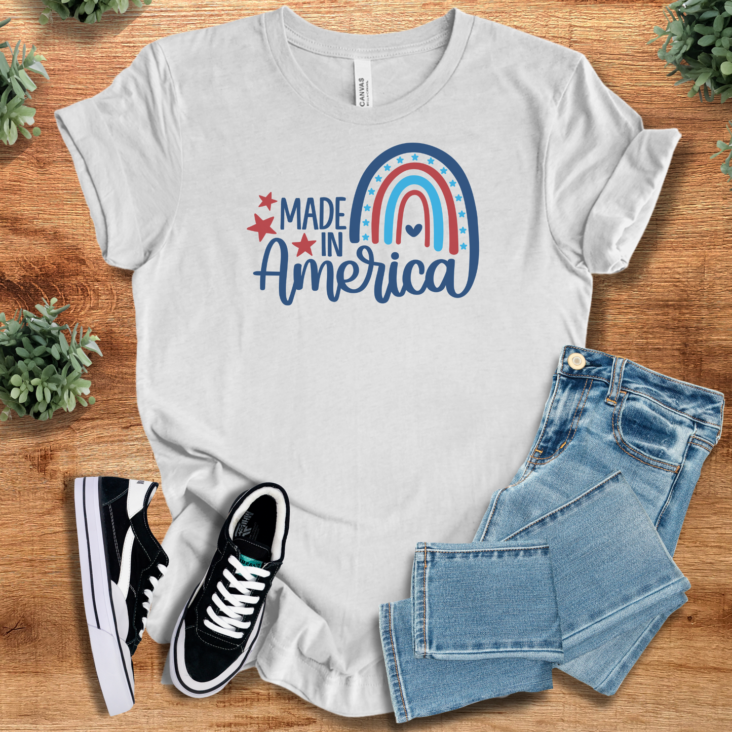 White t-shirt with '' text, flat lay styled on a wooden surface.