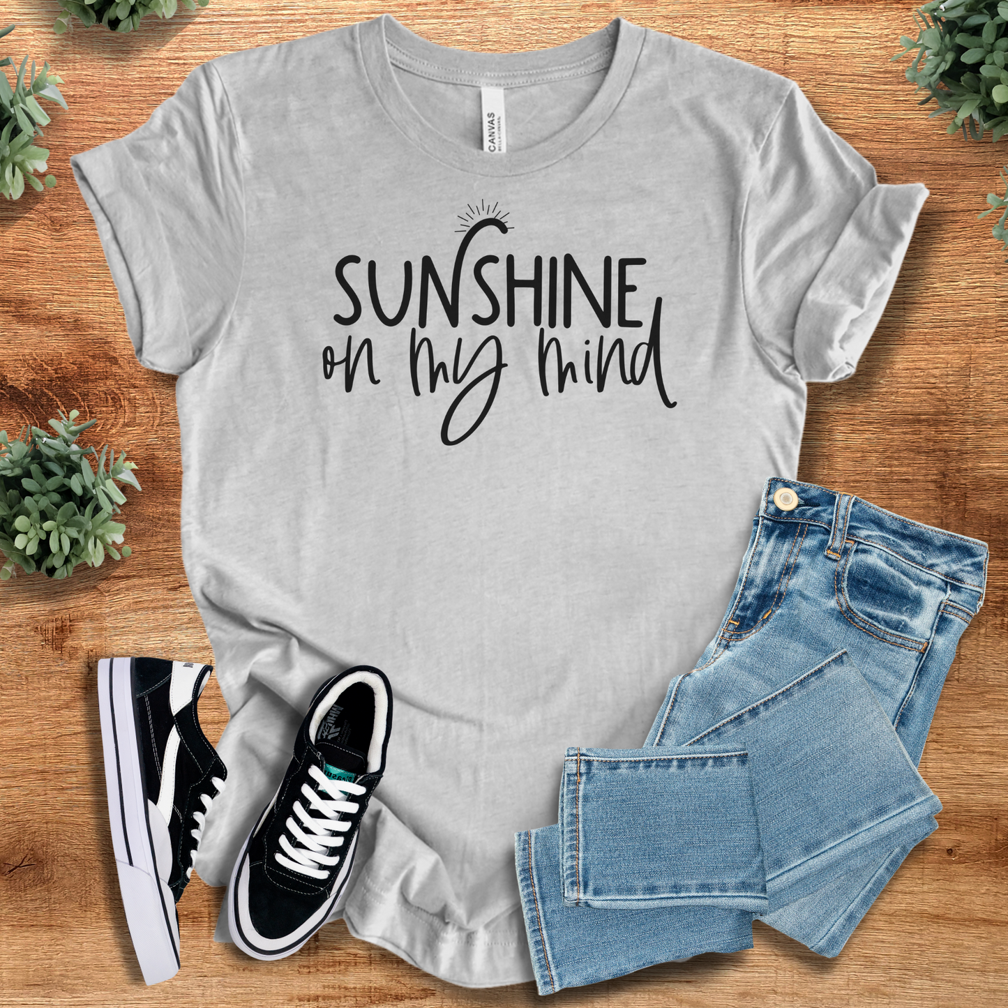 Yellow t-shirt with '' text, flat lay styled on a wooden surface.