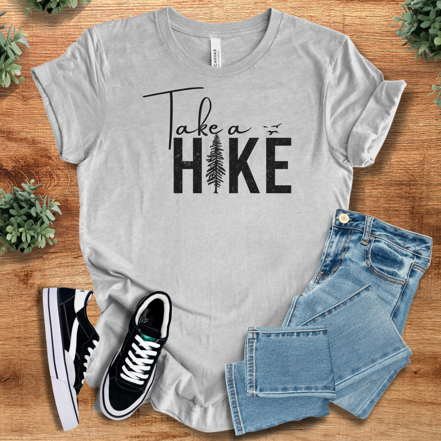 Athletic-heather t-shirt with 'Take A Hike T‑Shirt' text, flat lay styled on a wooden surface.