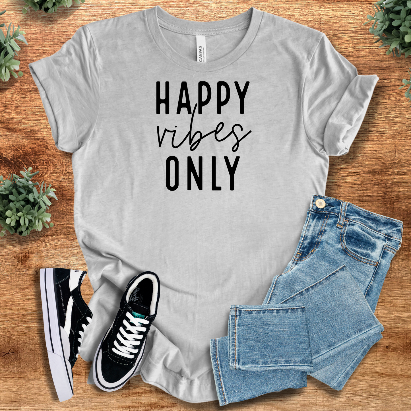 Happy Vibes Only Tee in heather gray with black text, paired with jeans and sneakers. Positive vibes Airlume cotton shirt for relaxed daily wear.