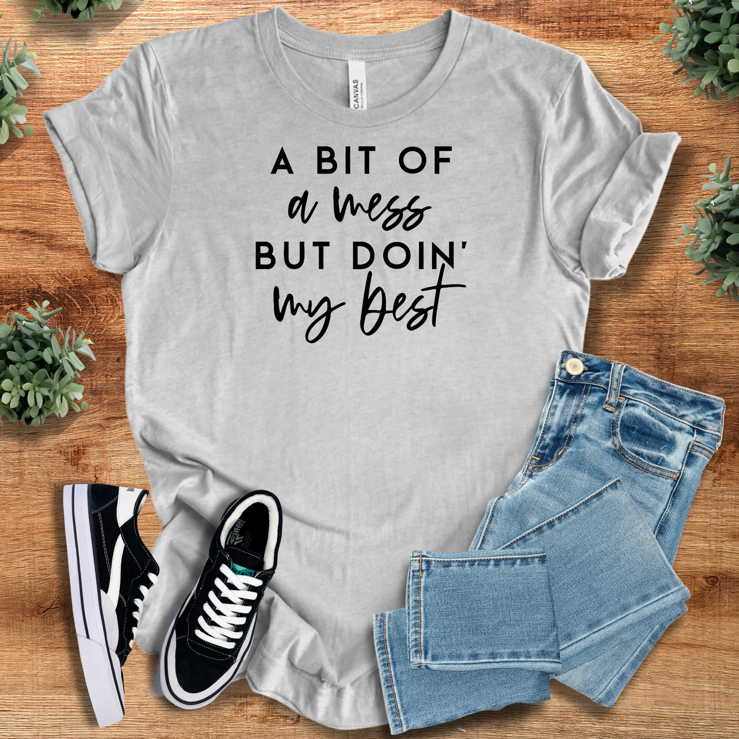 Black t-shirt with '' text, flat lay styled on a wooden surface.