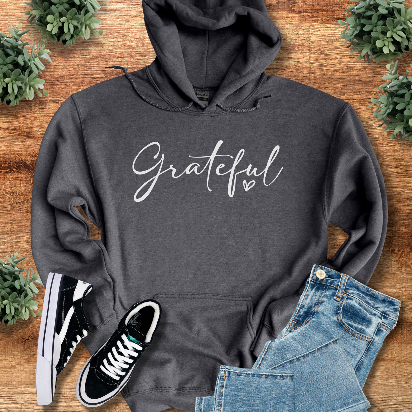 Navy t-shirt with '' text, flat lay styled on a wooden surface.