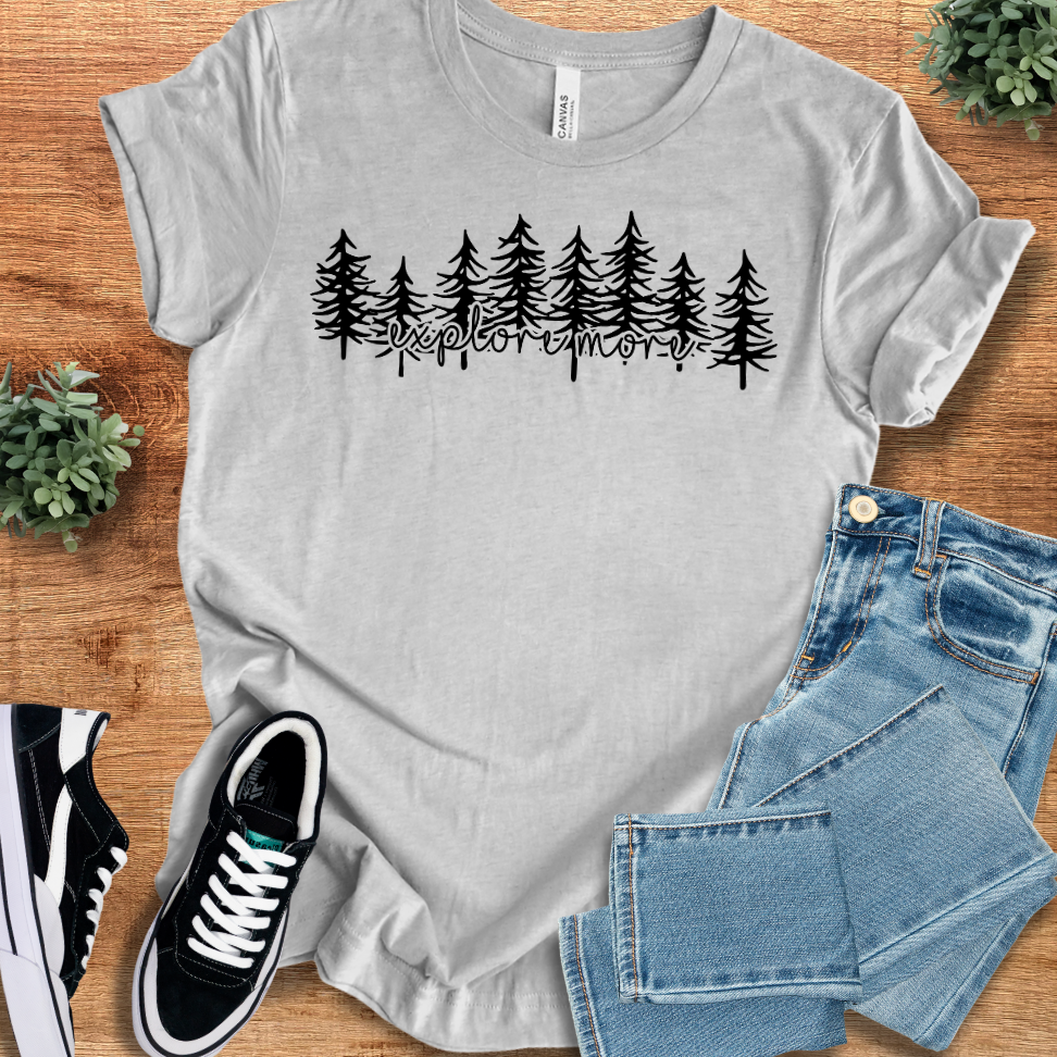 Athletic-heather t-shirt with 'Explore More T‑Shirt' text, flat lay styled on a wooden surface.