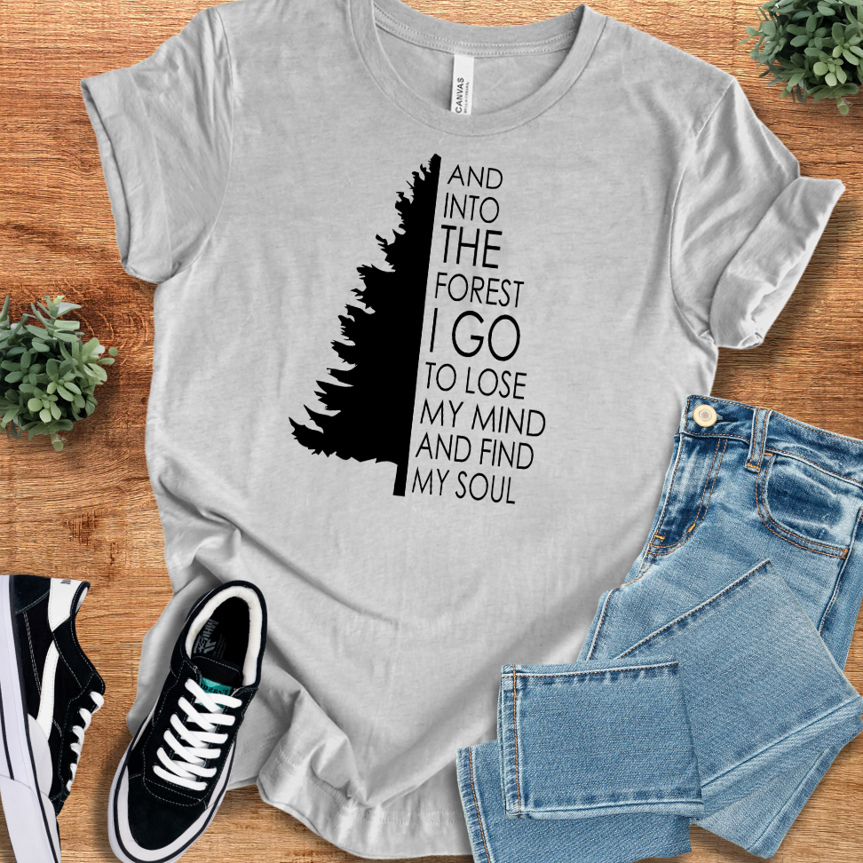Athletic-heather t-shirt with 'Into The Forest I Go T‑Shirt' text, flat lay styled on a wooden surface.