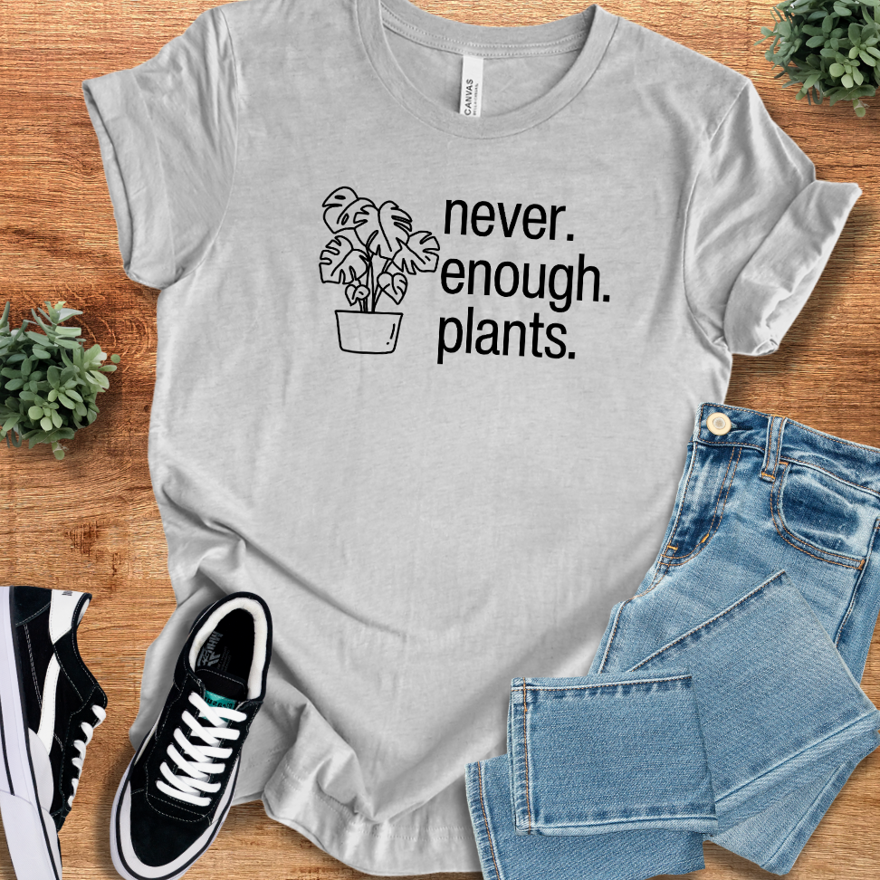 Athletic-heather t-shirt with 'Never Enough Plants T‑Shirt' text, flat lay styled on a wooden surface.