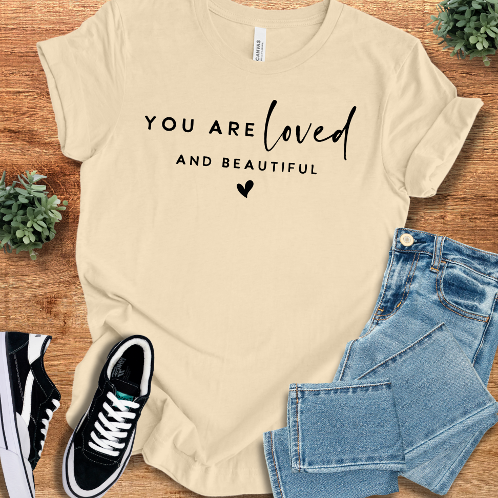 Heather-mauve t-shirt with '' text, flat lay styled on a wooden surface.