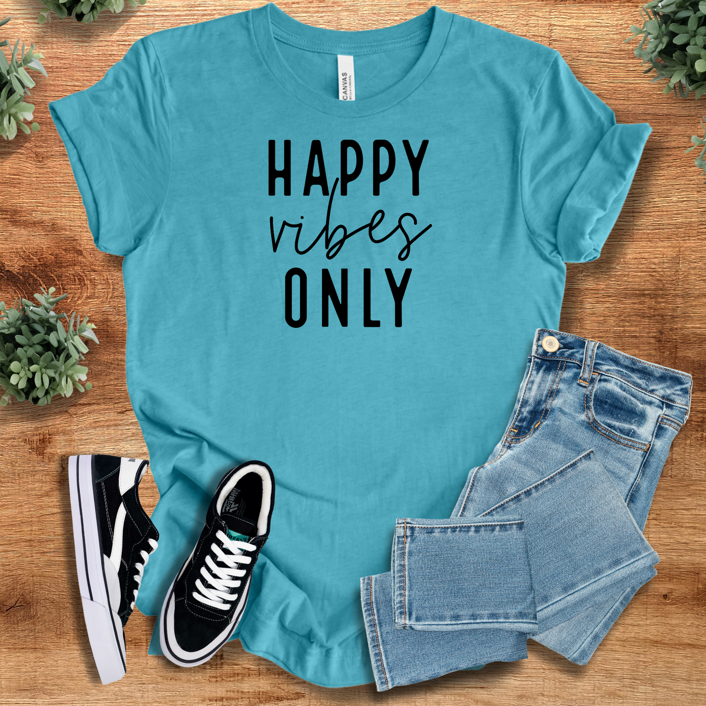 Happy Vibes Only Tee in turquoise blue with black text, styled with jeans and sneakers. Fun graphic Airlume cotton tee for spreading happy vibes.