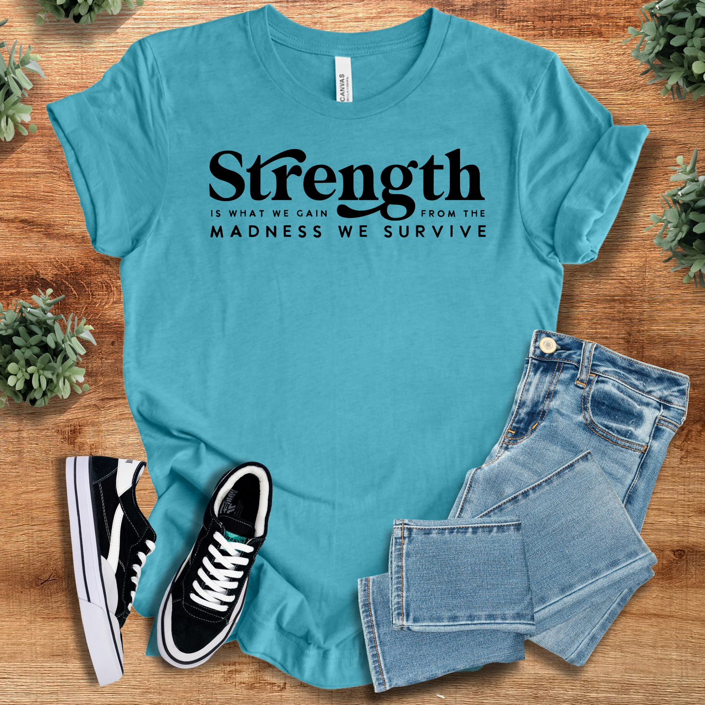 Aqua blue unisex strength tee featuring empowering quote, paired with denim and sneakers. Ideal inspirational apparel for mindset and resilience.