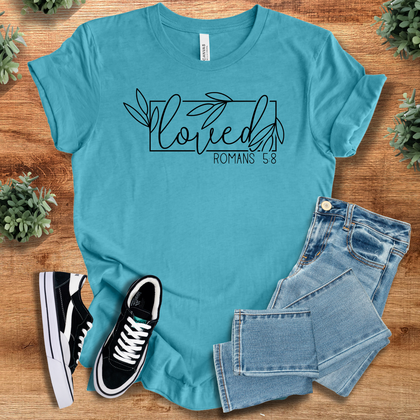 Turquoise Loved Romans 5:8 Tee with elegant Christian quote design, unisex scripture shirt styled with denim and black sneakers.