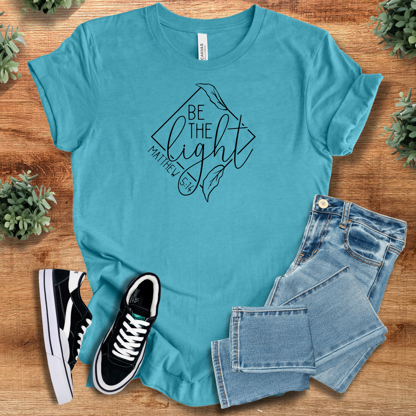 Aqua blue Be the Light Matthew 5:14 T-shirt in soft cotton, showcasing faith-inspired design with jeans and black sneakers.