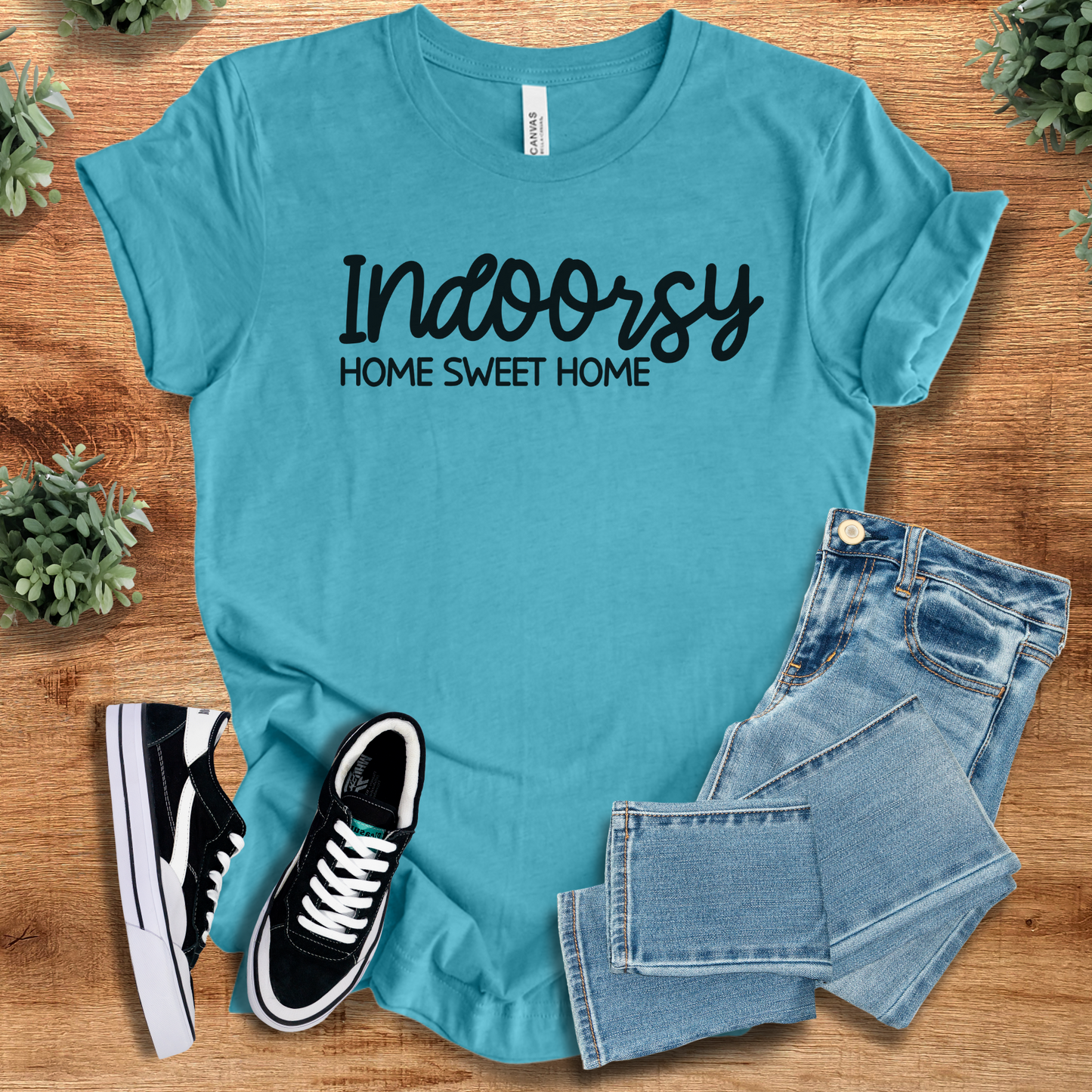 Heather-aqua t-shirt with 'Indoorsy T‑Shirt' text, flat lay styled on a wooden surface.