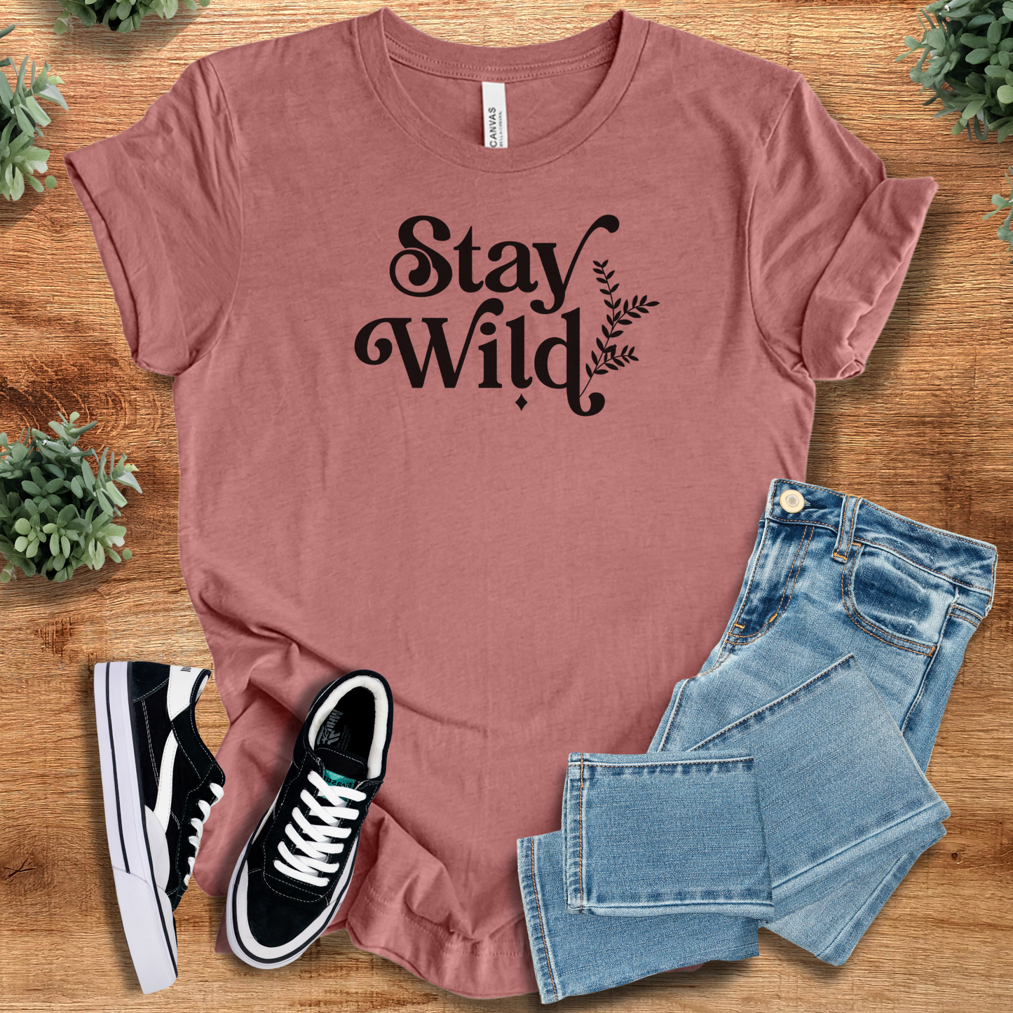 Heather-mauve t-shirt with 'Stay Wild T‑Shirt' text, flat lay styled on a wooden surface.