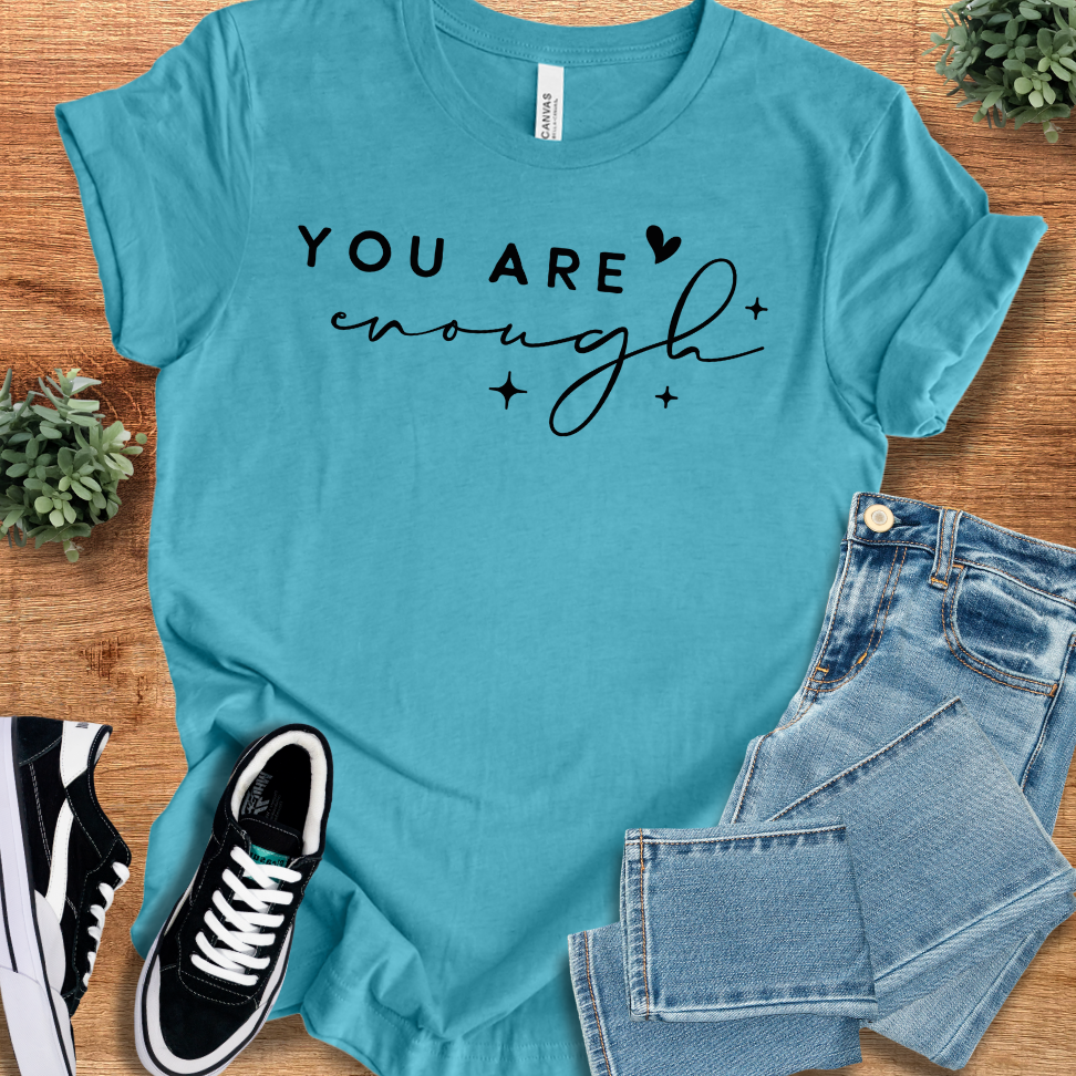 Heather-mauve t-shirt with '' text, flat lay styled on a wooden surface.