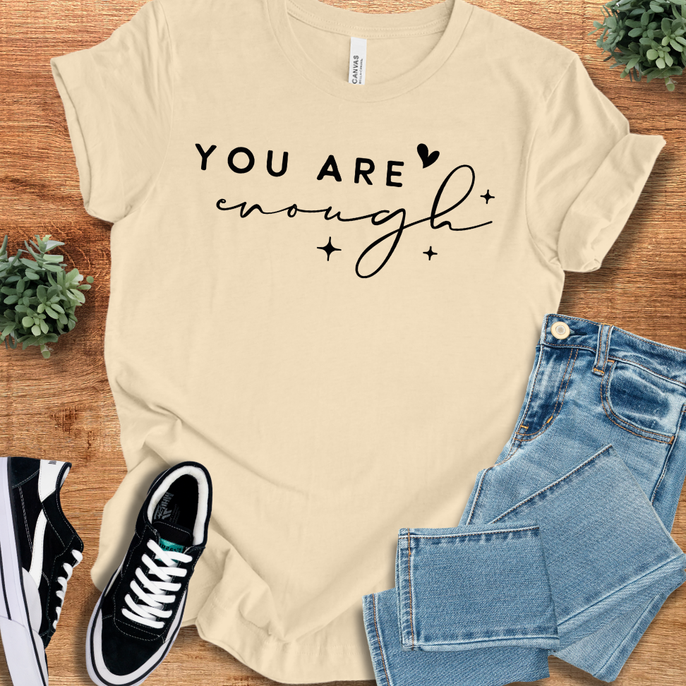 Heather-mauve t-shirt with '' text, flat lay styled on a wooden surface.