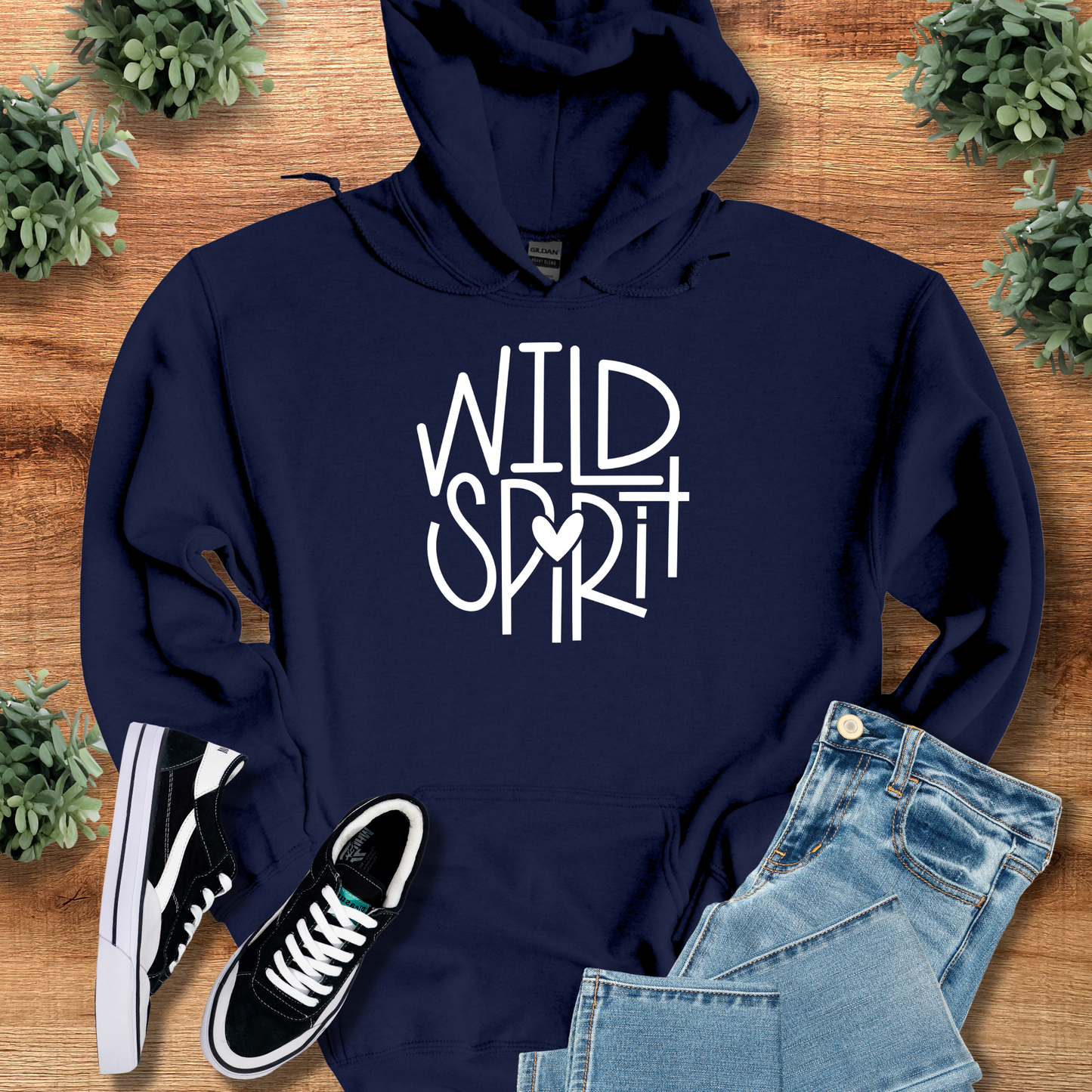 Wild Spirit Hoodie for Outdoor and Casual Wear in navy blue with bold white graphic text, styled with jeans and sneakers on a rustic wood background.