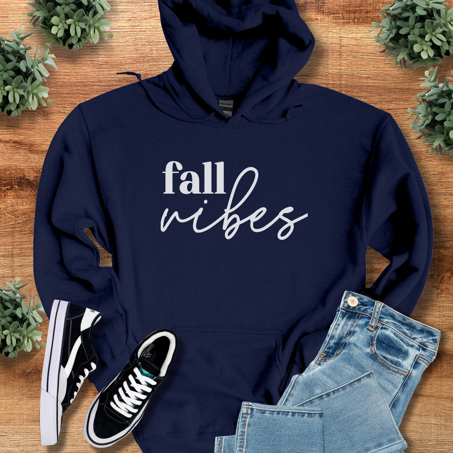 Navy t-shirt with '' text, flat lay styled on a wooden surface.