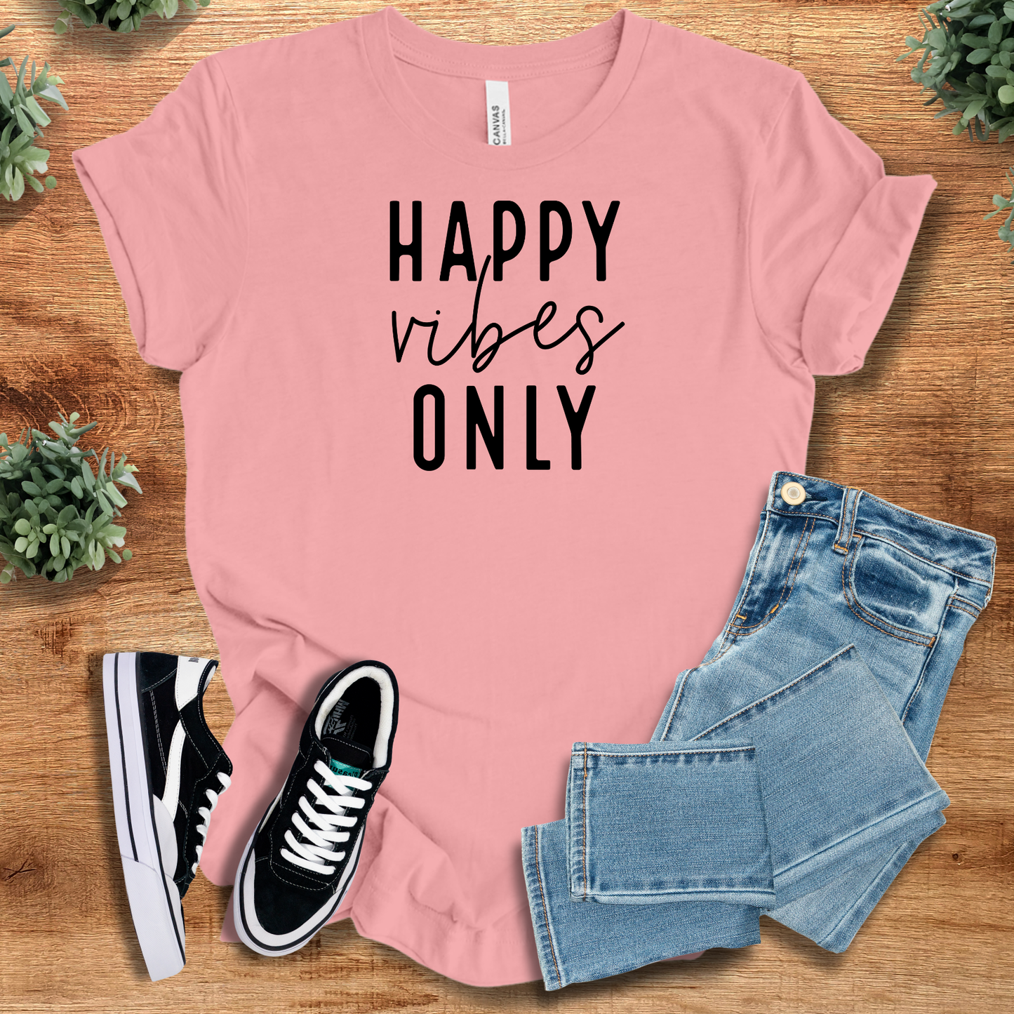 Happy Vibes Only Tee in light pink with black text, matched with jeans and sneakers. Feel-good Airlume cotton top for joyful and stylish outfits.