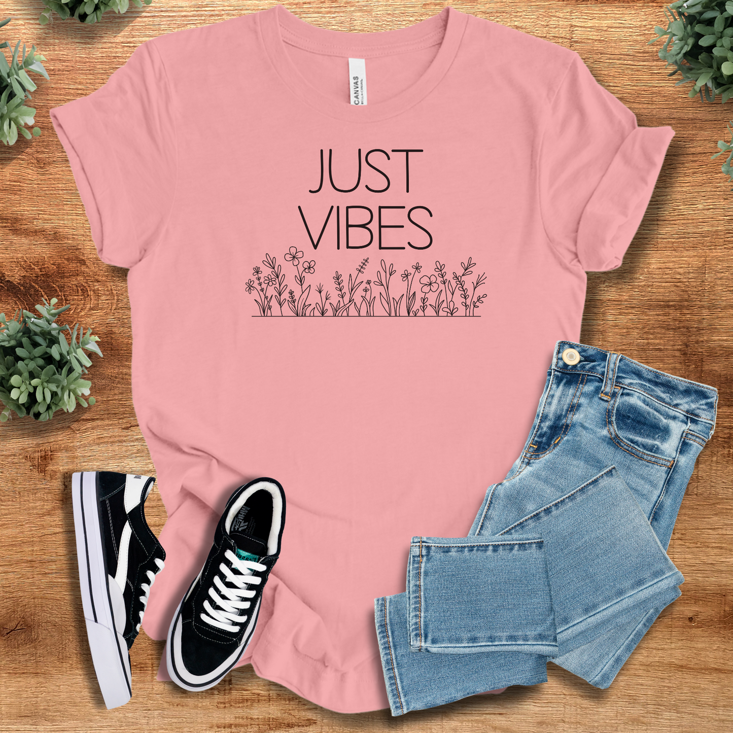 Pink Just Vibes Wildflower T‑Shirt on Bella+Canvas 3001. Comfy minimalist floral tee styled with jeans and black sneakers for casual wear.