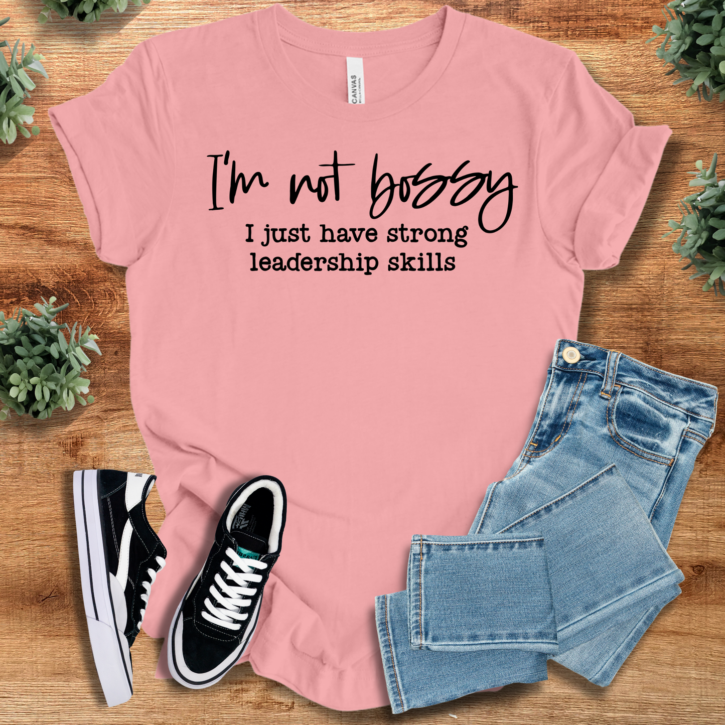 pink t-shirt with '' text, flat lay styled on a wooden surface.
