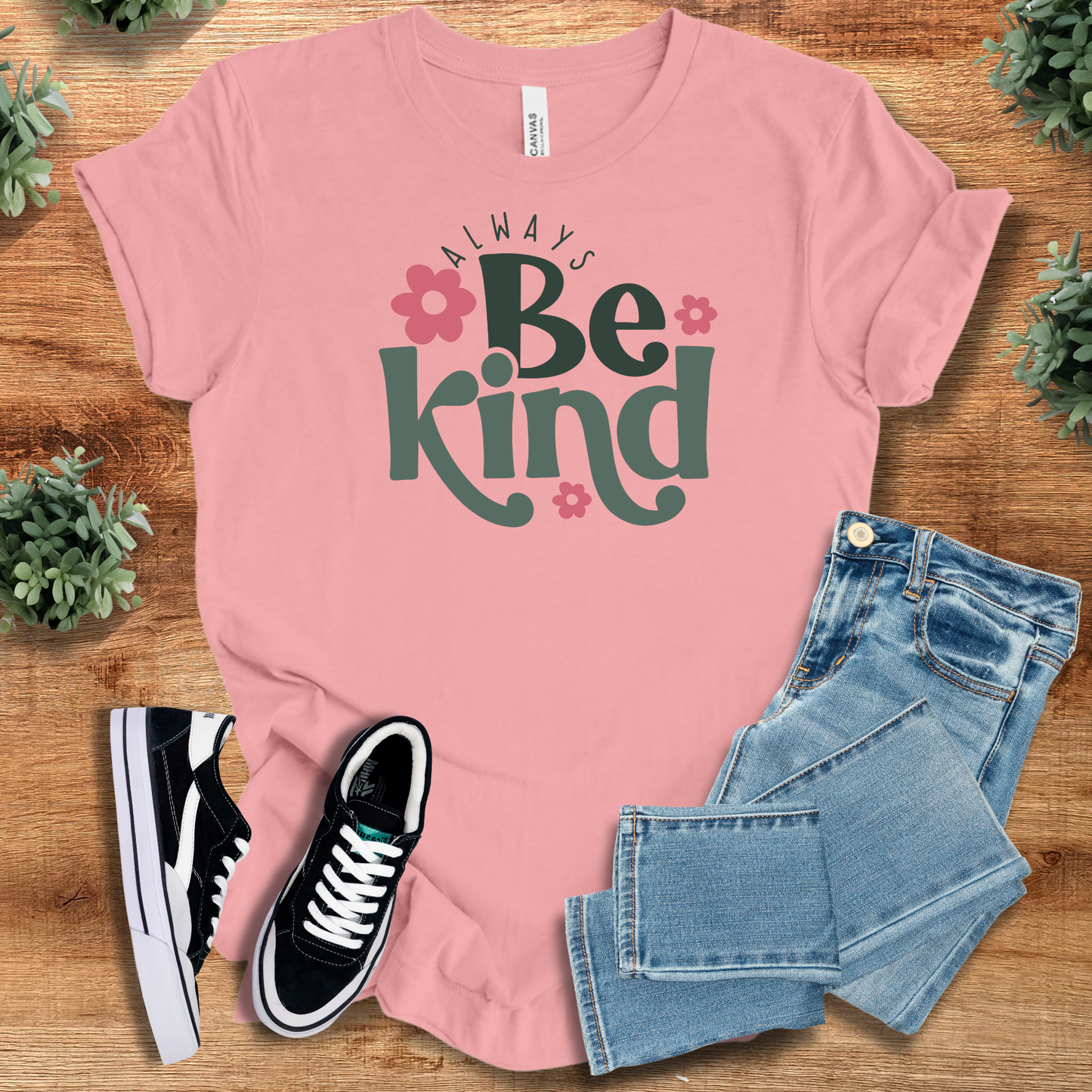 Always Be Kind - Unisex Kindness Tee in pink featuring bold text and flowers, paired with denim and shoes. Perfect inspirational gift idea.