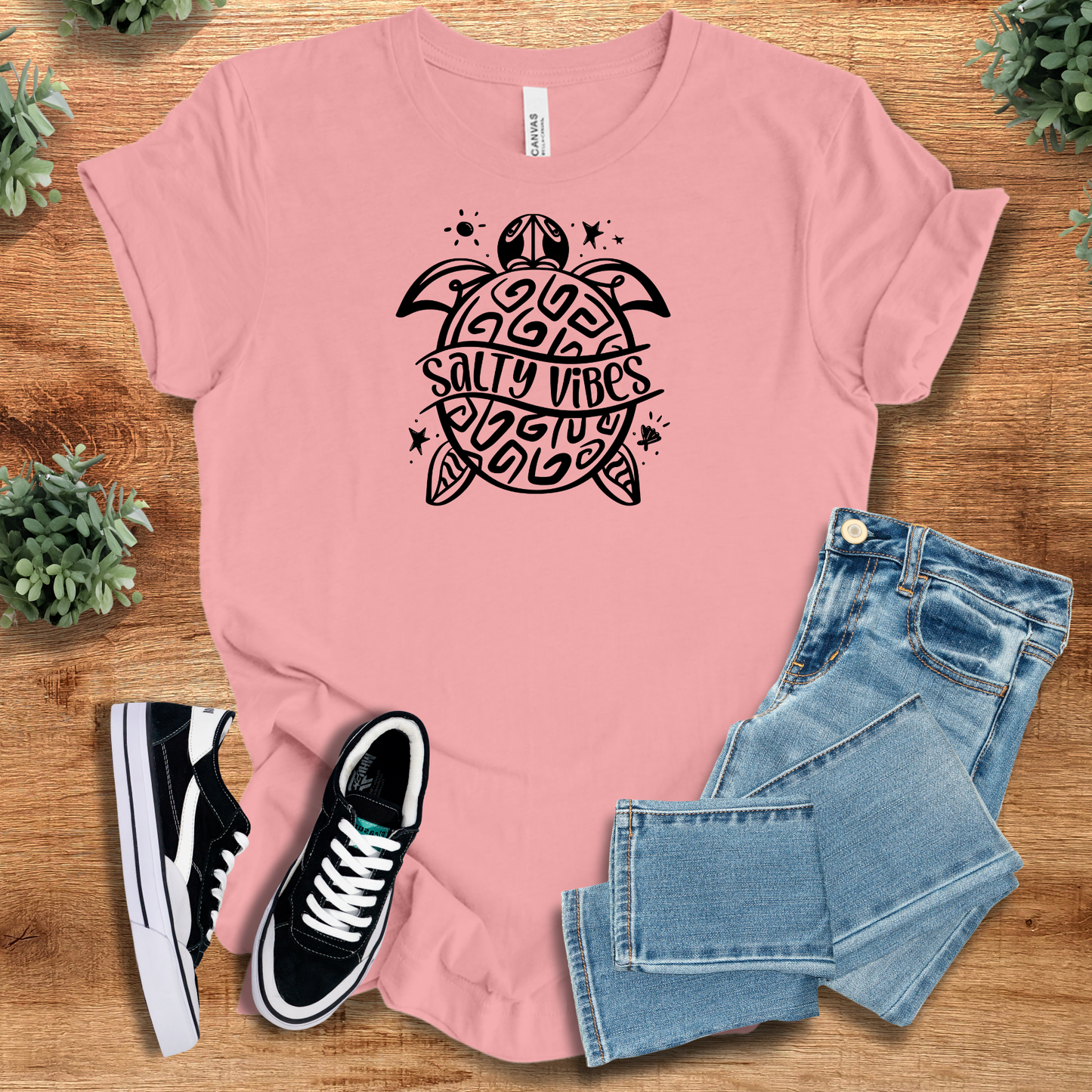 Heather-aqua t-shirt with '' text, flat lay styled on a wooden surface.