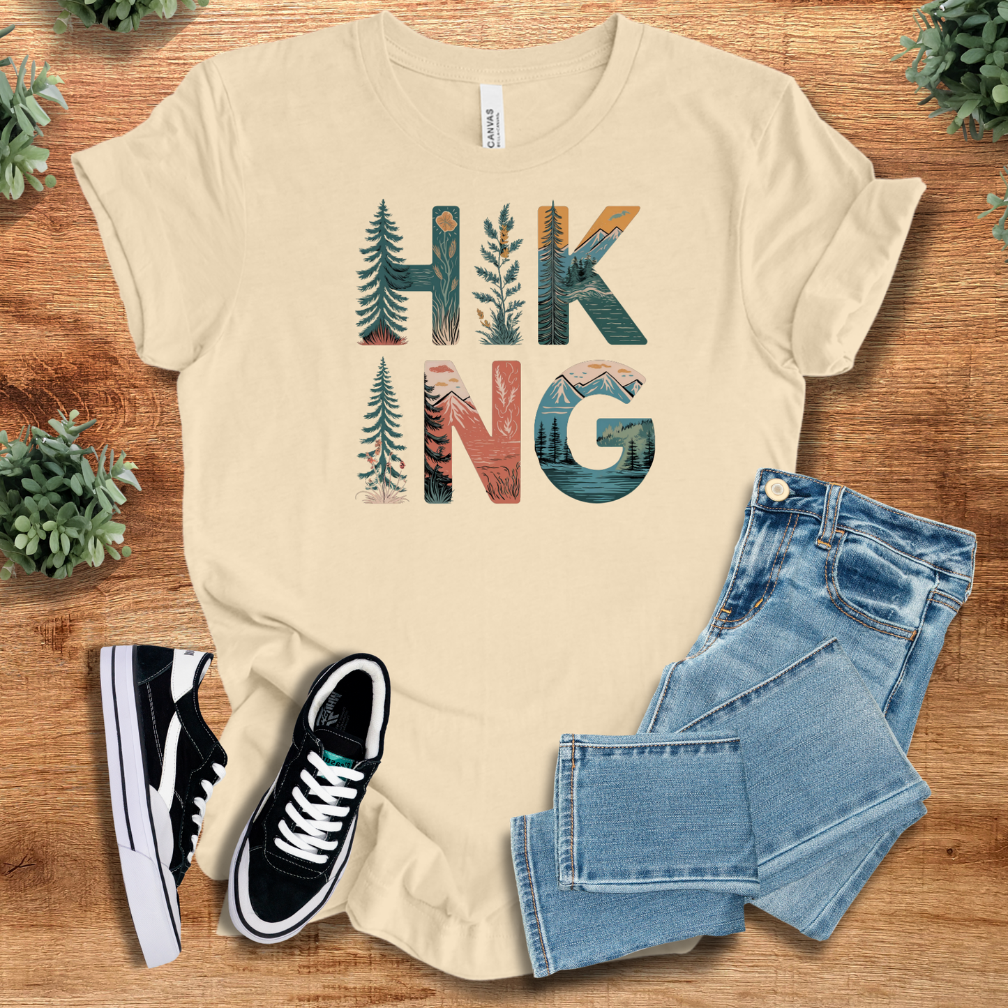 White t-shirt with '' text, flat lay styled on a wooden surface.