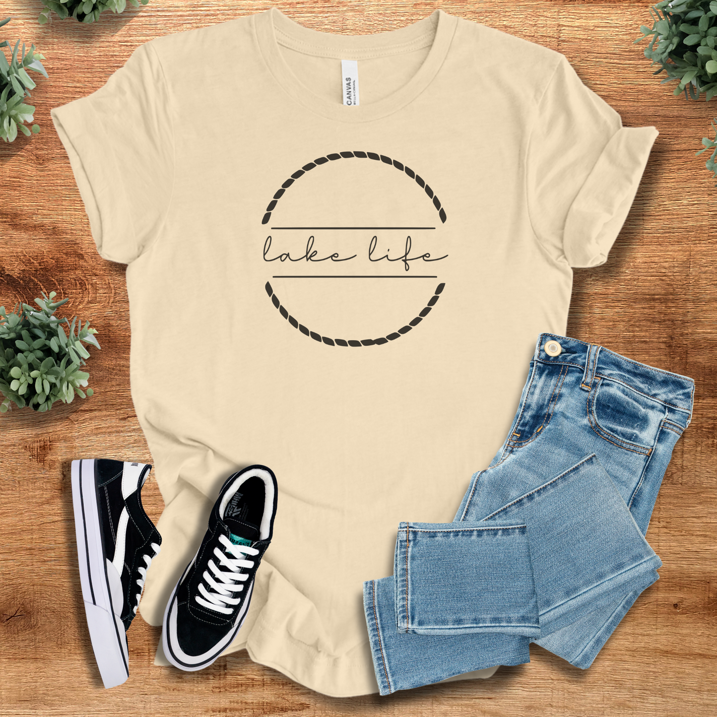 Military-green t-shirt with '' text, flat lay styled on a wooden surface.
