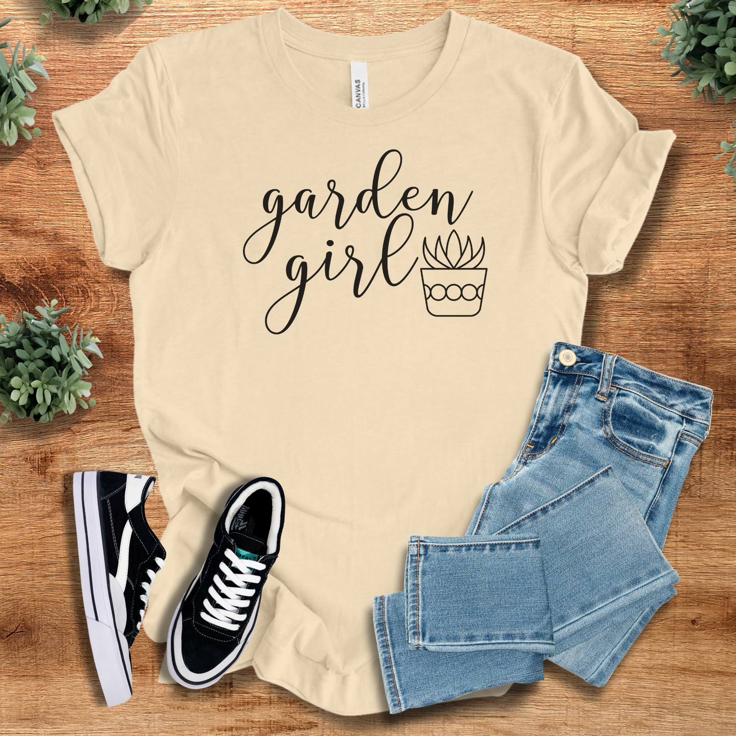 Soft-cream t-shirt with 'Garden Girl T‑Shirt' text, flat lay styled on a wooden surface.