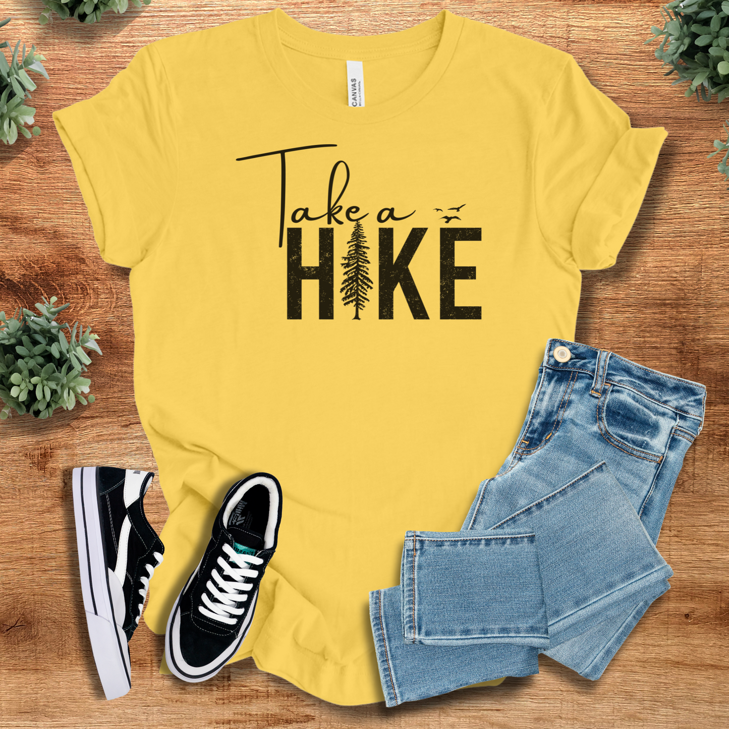 Military-green t-shirt with '' text, flat lay styled on a wooden surface.