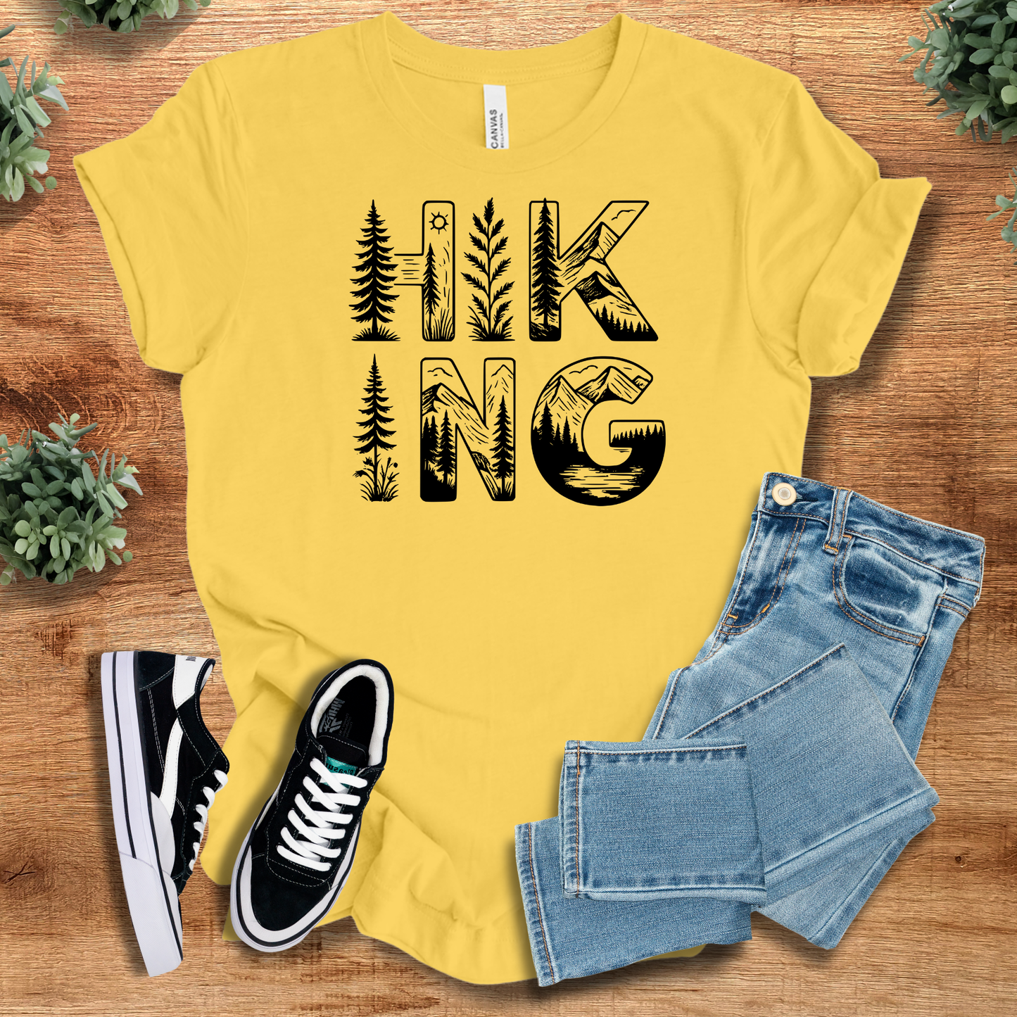 Military-green t-shirt with '' text, flat lay styled on a wooden surface.