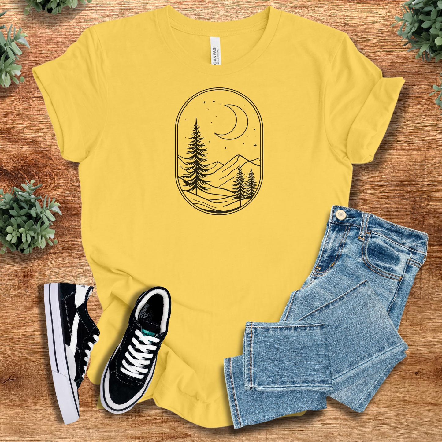 Military-green t-shirt with '' text, flat lay styled on a wooden surface.