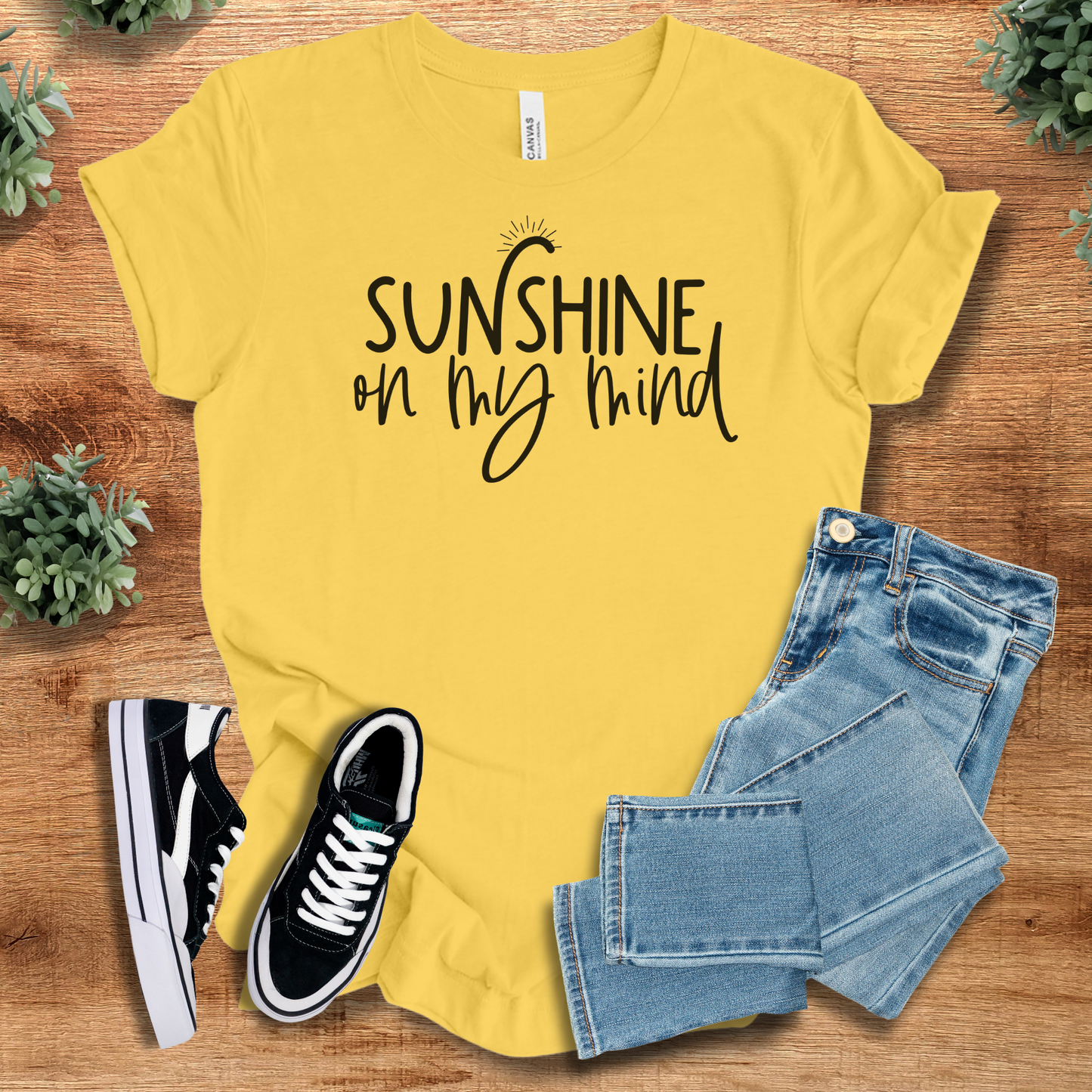 Yellow t-shirt with 'Sunshine On My Mind T‑Shirt' text, flat lay styled on a wooden surface.