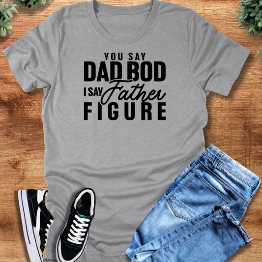 Athletic-heather t-shirt with 'Father Figure Tee T‑Shirt' text, flat lay styled on a wooden surface.