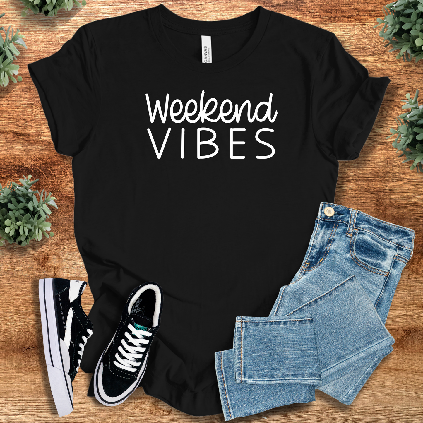 White t-shirt with '' text, flat lay styled on a wooden surface.