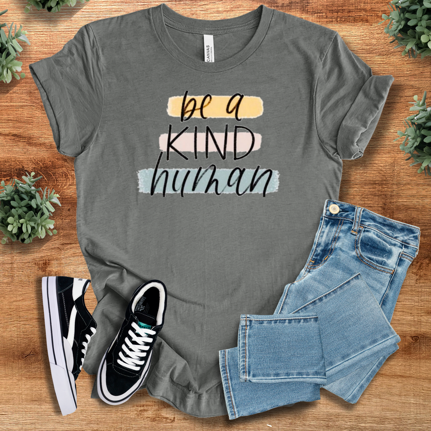 White t-shirt with '' text, flat lay styled on a wooden surface.