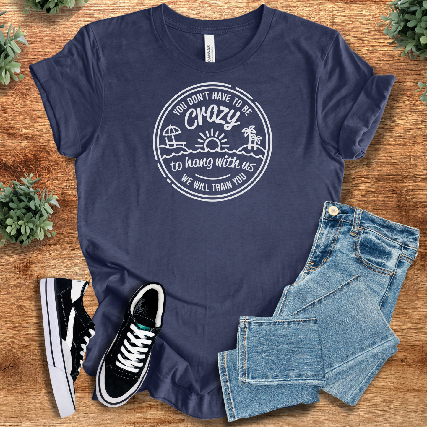 Funny graphic tee in navy with 'You Don’t Have to be Crazy, We'll Train You' quote. Unisex humor shirt ideal for group trips or casual wear.