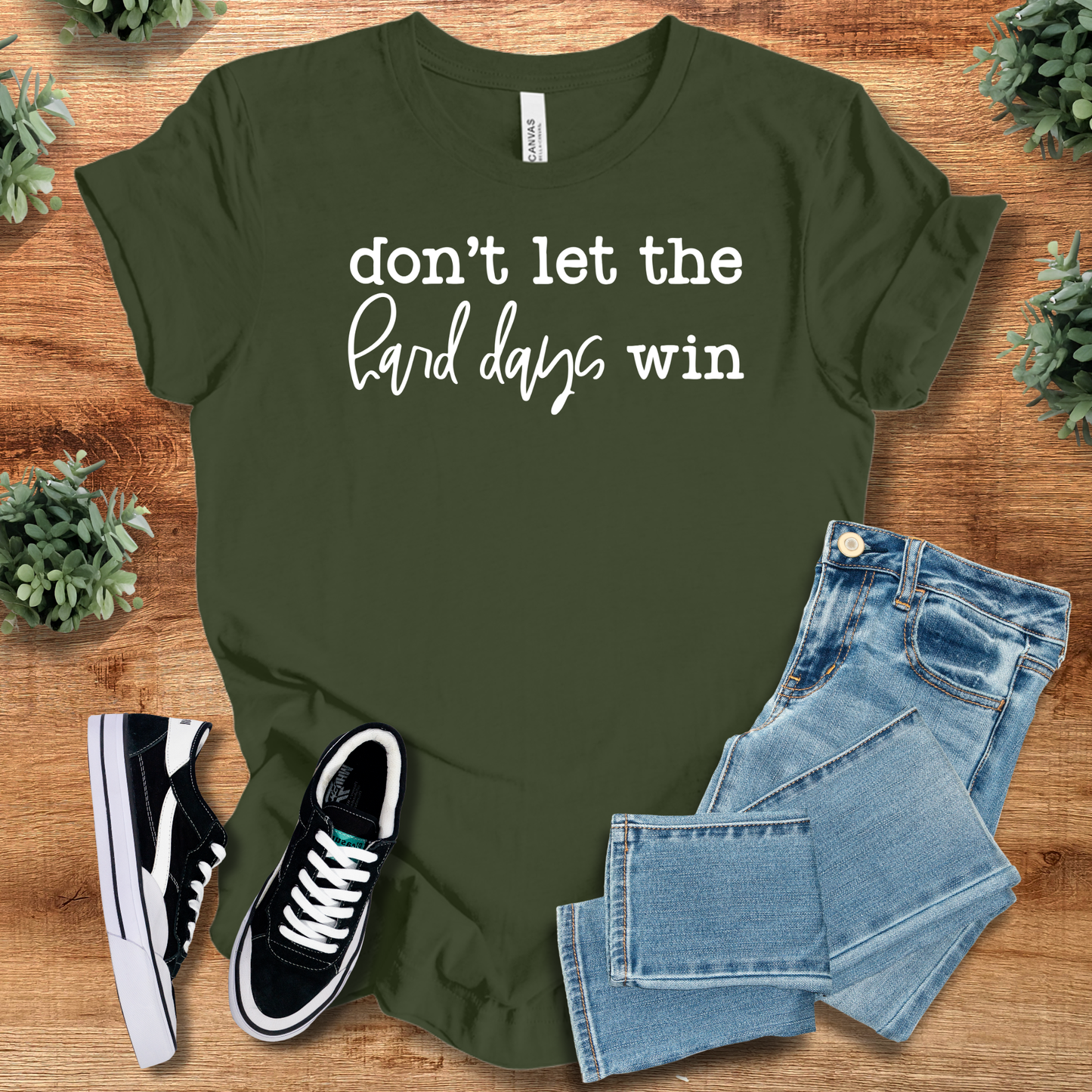 Olive green Don't Let Hard Days Win cotton T-Shirt featuring white text, styled with jeans and shoes for a positive mental health look.