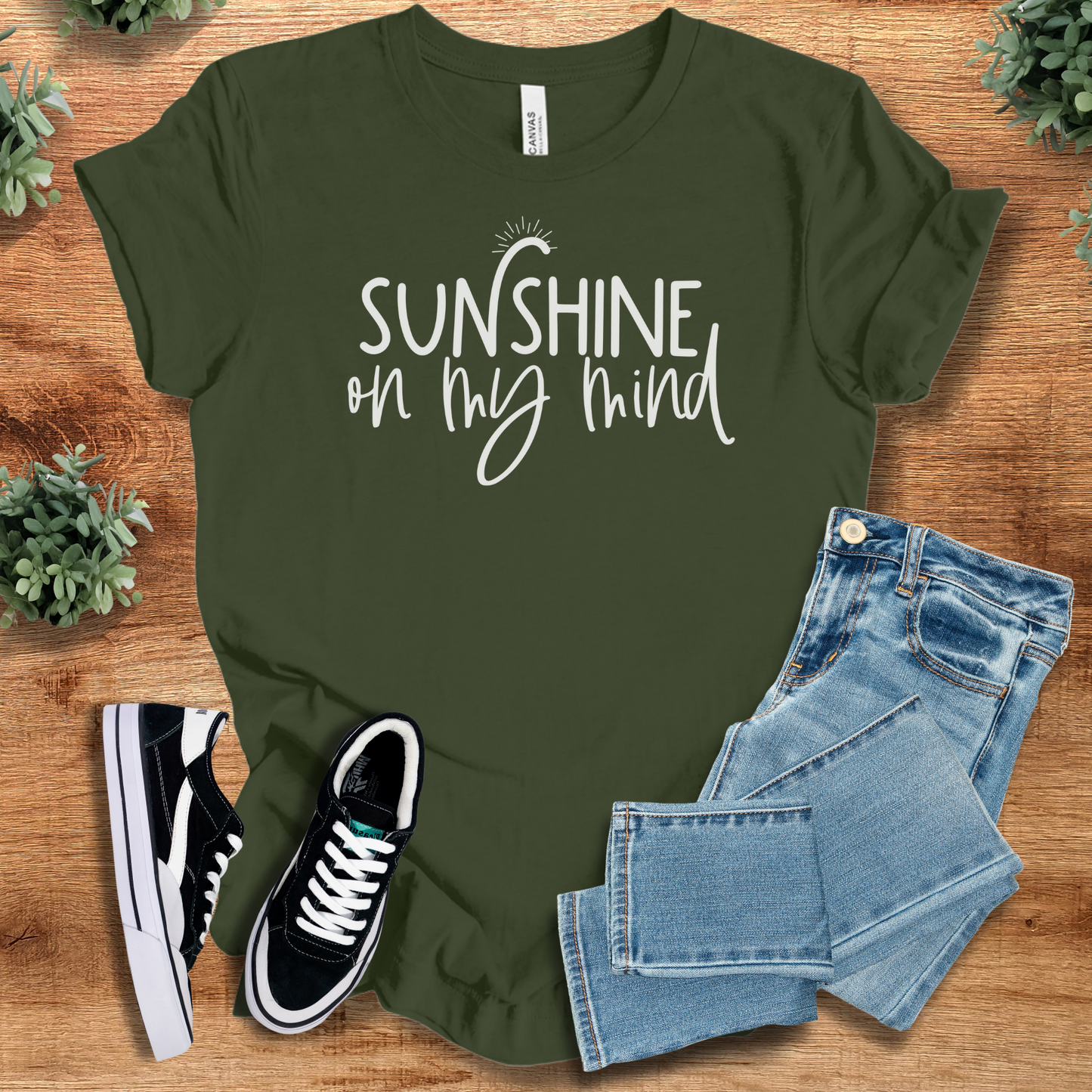 Yellow t-shirt with '' text, flat lay styled on a wooden surface.
