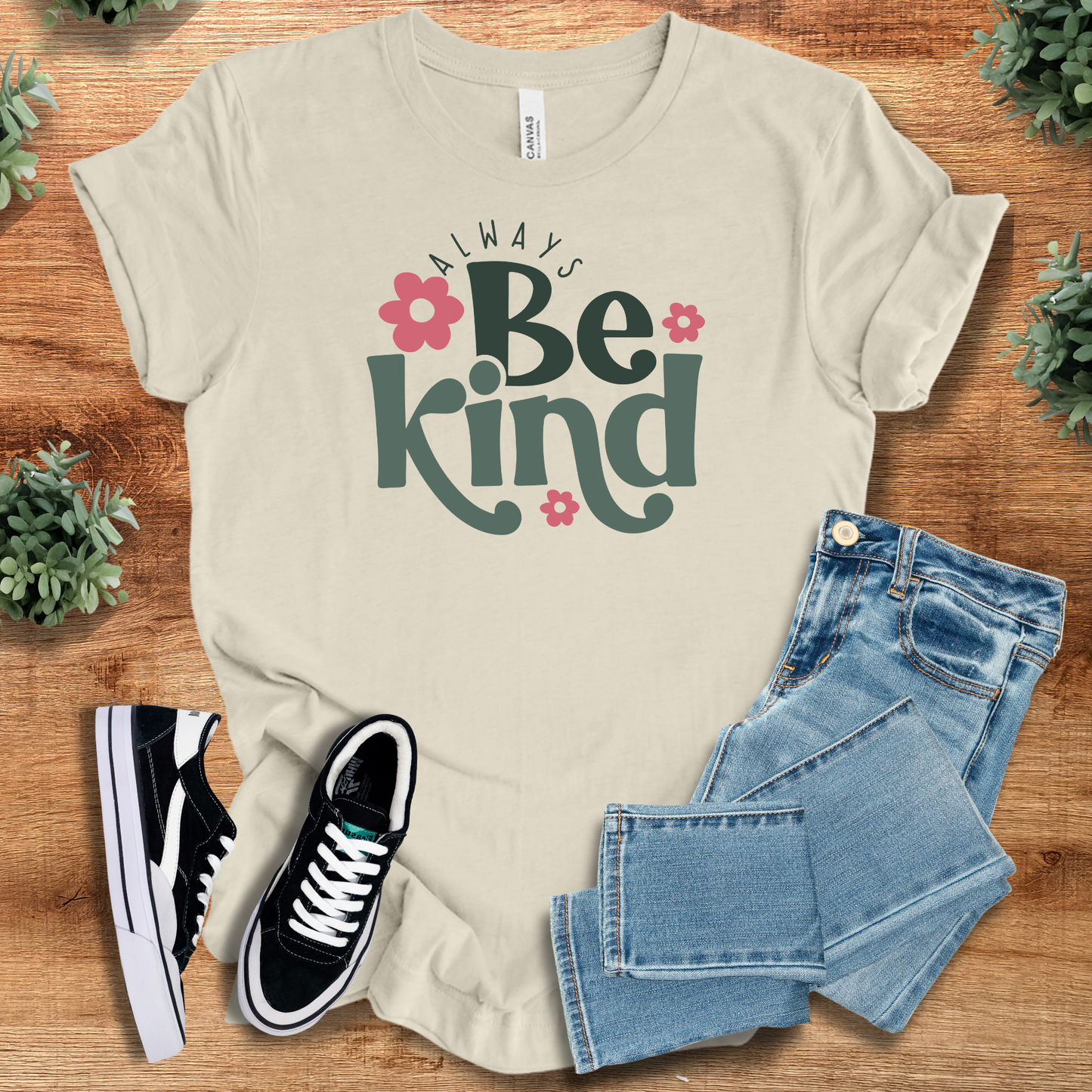 Always Be Kind - Unisex Kindness Tee in beige with floral graphic, laid out with jeans and sneakers. Comfortable and uplifting casual top.