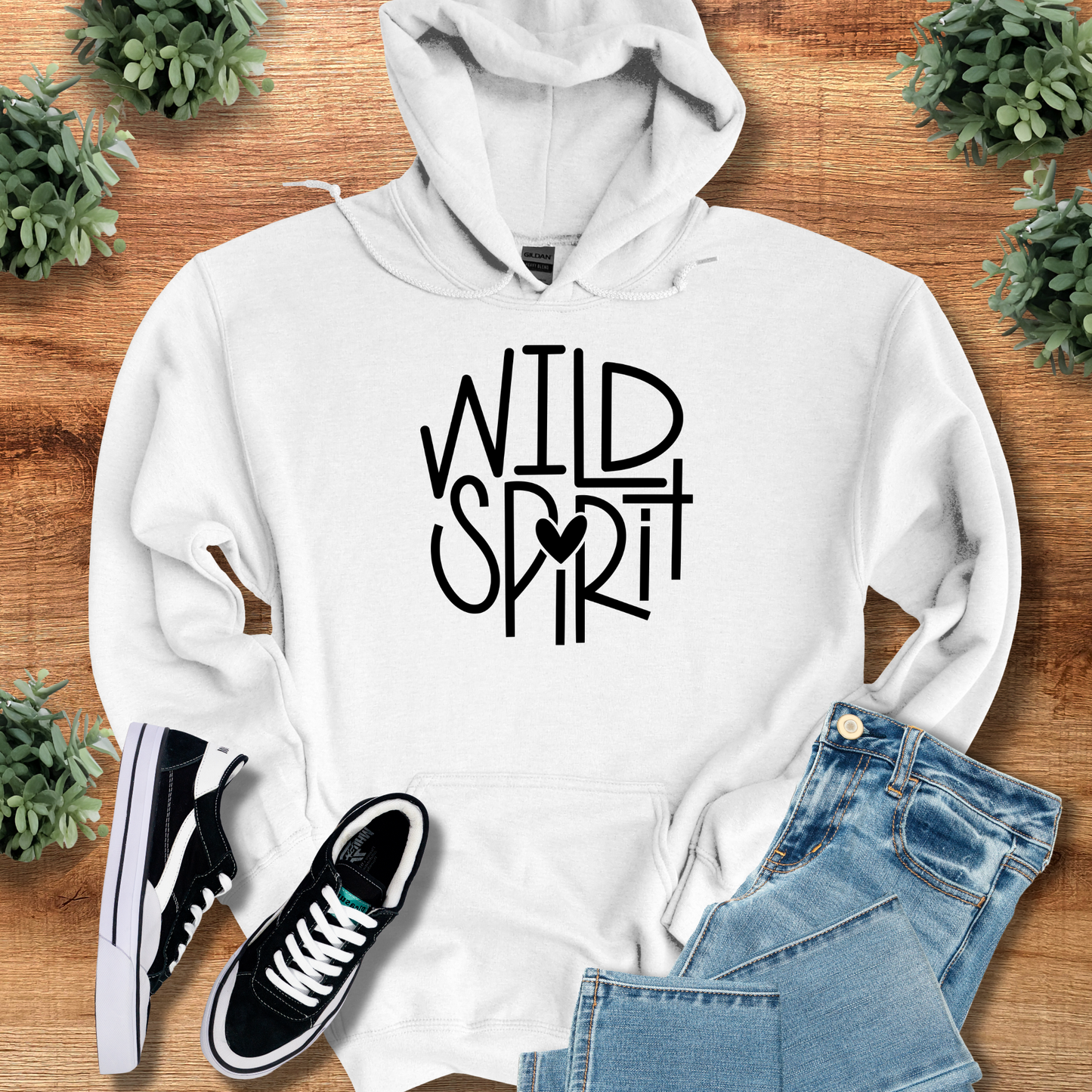 Wild Spirit Hoodie for Outdoor and Casual Wear in white with bold black typography and heart detail, styled with jeans and sneakers on wood background.