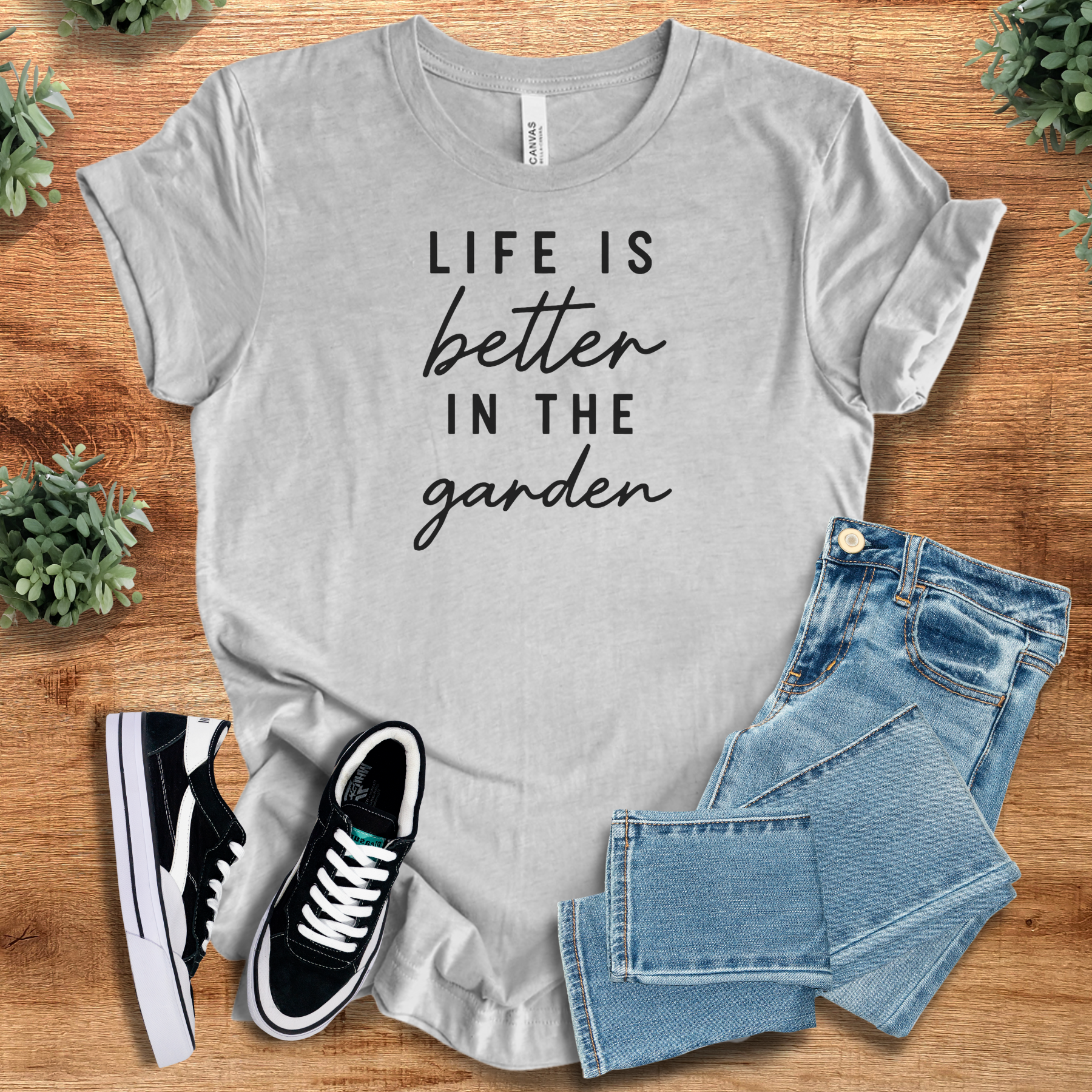 Military-green t-shirt with '' text, flat lay styled on a wooden surface.
