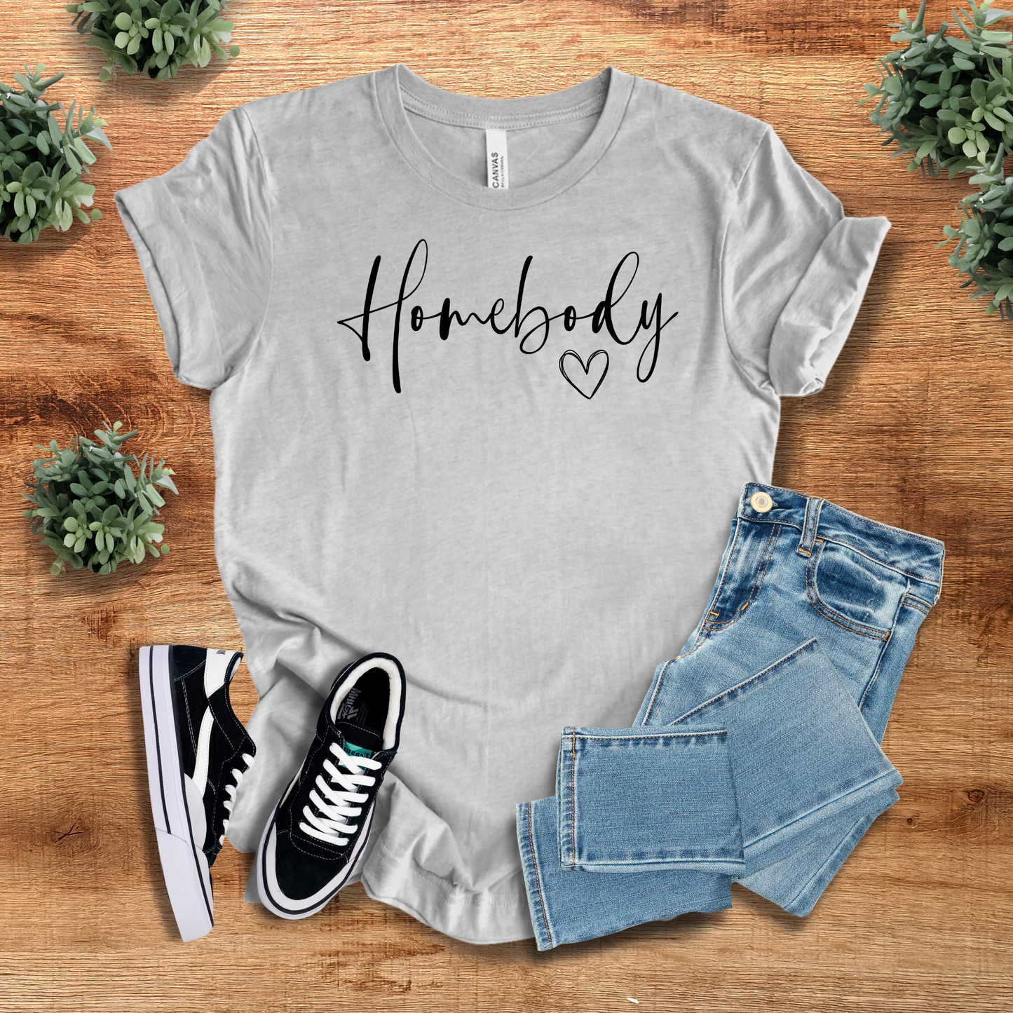 Heather gray Homebody Graphic T-Shirt with a minimalist aesthetic, laid out with denim jeans and sneakers. Perfect for relaxed and cozy outfits.
