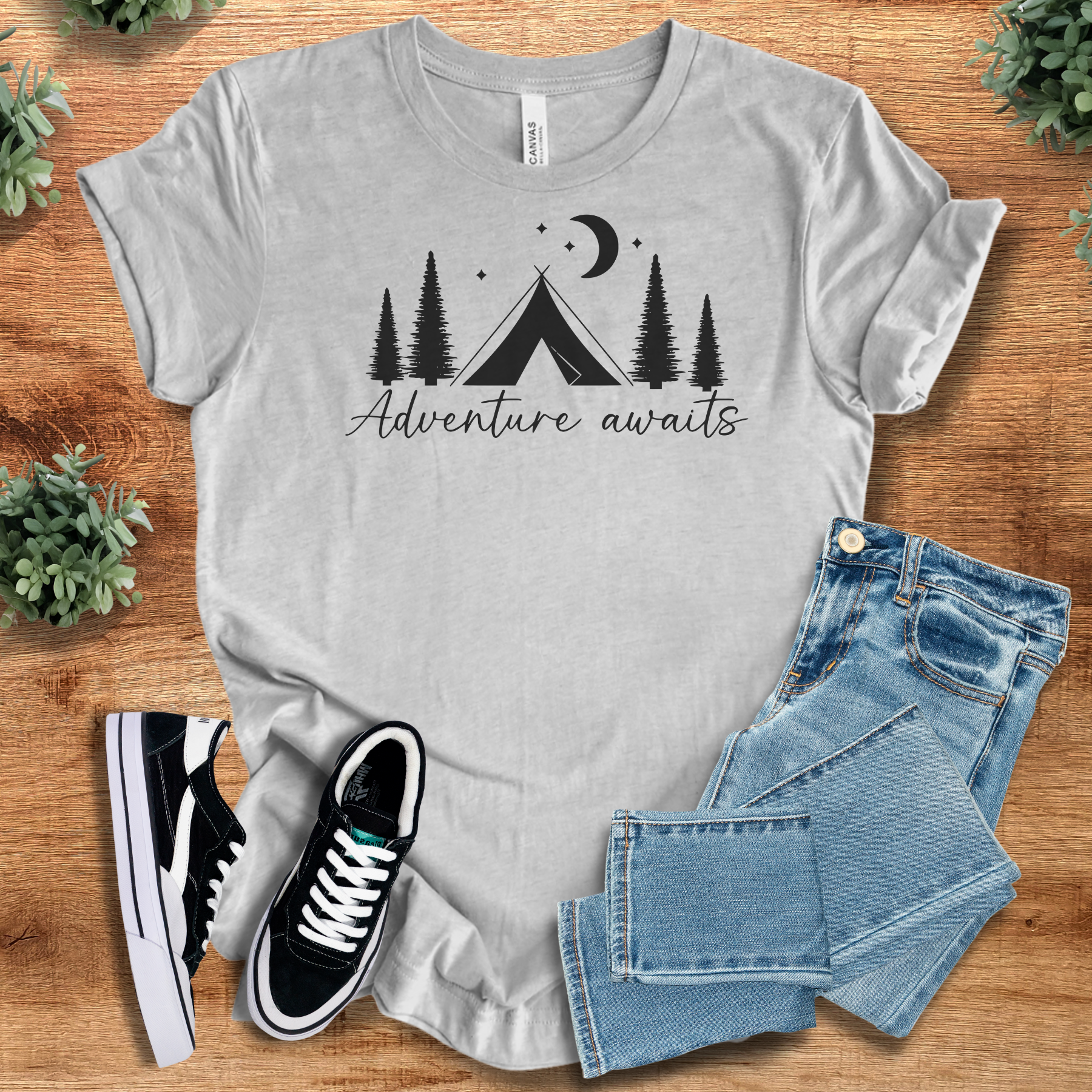 Military-green t-shirt with '' text, flat lay styled on a wooden surface.