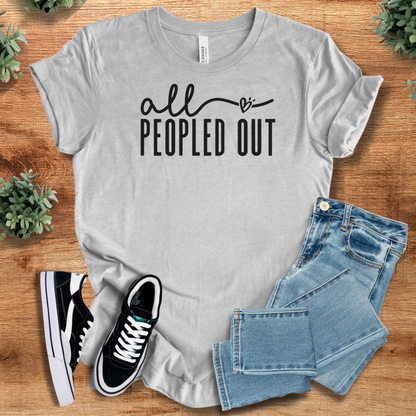 Athletic-heather t-shirt with 'All Peopled Out T‑Shirt' text, flat lay styled on a wooden surface.
