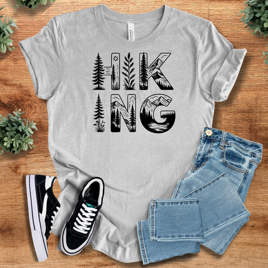 Light gray Hiking Tee with bold black forest-themed 'HIKING' print. 100% cotton, breathable t-shirt for nature lovers and outdoor adventures.