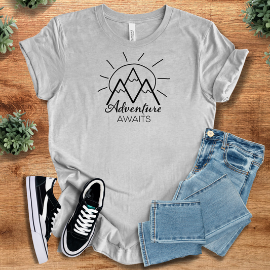 Adventure Awaits T-shirt in light gray with mountain and sun graphic, 100% cotton breathable travel tee for outdoor enthusiasts.