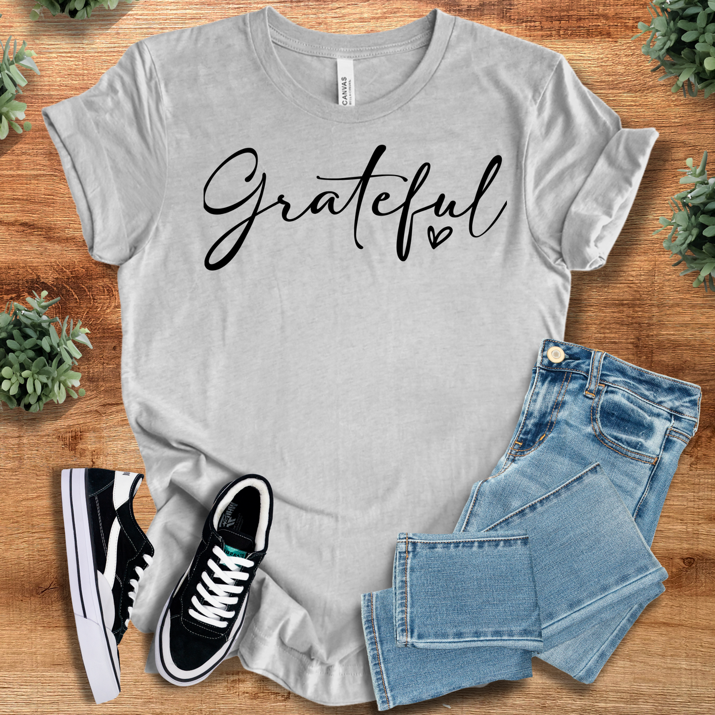 Black t-shirt with '' text, flat lay styled on a wooden surface.