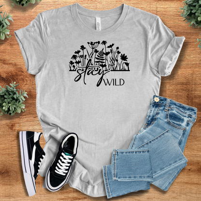 Athletic-heather t-shirt with 'Stay Wild T‑Shirt' text, flat lay styled on a wooden surface.